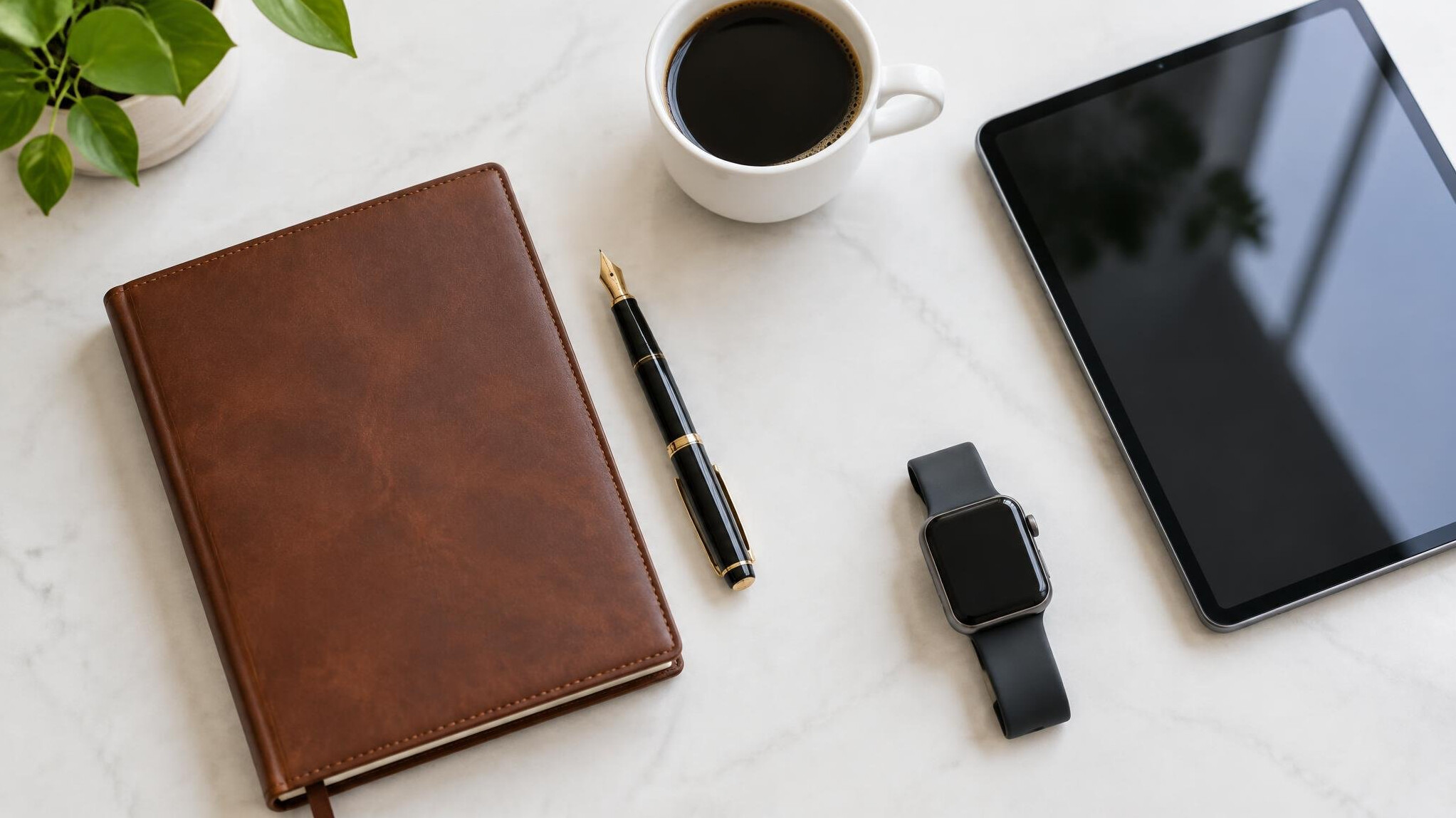 Top view of a tidy executive desk with notebook, pen, tablet and coffee cup