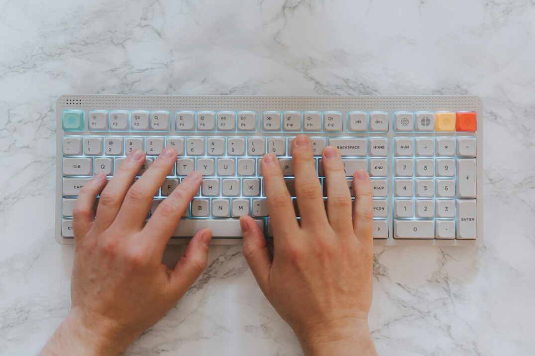 Hands typing on a laptop on a bright desk with notebook